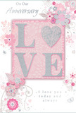 The anniversary card depicted here is a tender tribute to enduring romance, its soft pastel pinks and silvery greys blending to create a quiet, intimate atmosphere akin to a peaceful walk through South Hill Park in Bracknell Forest. The focal point is the word LOVE, with each letter raised from the surface and gently coated in shimmering glitter. In place of the letter O, a textured silver heart sits proudly, its gleaming surface drawing the eye and suggesting the steady, central place of love in a shared life. Around this central word, delicate blossoms appear in shades of blush, mauve, and creamy white, painted with an almost watercolour softness. Their edges blur slightly into the background, giving the impression of petals softened by light mist on an early morning. The stems and leaves curve in elegant arcs, intertwining like the stems of a romantic bouquet prepared for anniversary delivery across Bracknell, from Great Hollands to Hanworth. Small, graceful flourishes-scattered petals, slender swirls, and subtle butterflies-float around the flowers, creating movement as if a gentle breeze were passing through a spring garden. The backdrop remains a quiet blush pink, against which hints of silver glint gently, never overpowering the calm mood. Phrases such as On Our Anniversary and I love you today and always are written in a flowing script that mirrors the curves of the vines and flourishes. The overall design feels like a softly spoken promise-a keepsake that celebrates years of shared memories and companionship in the comforting, green-edged neighbourhoods of Bracknell Forest.